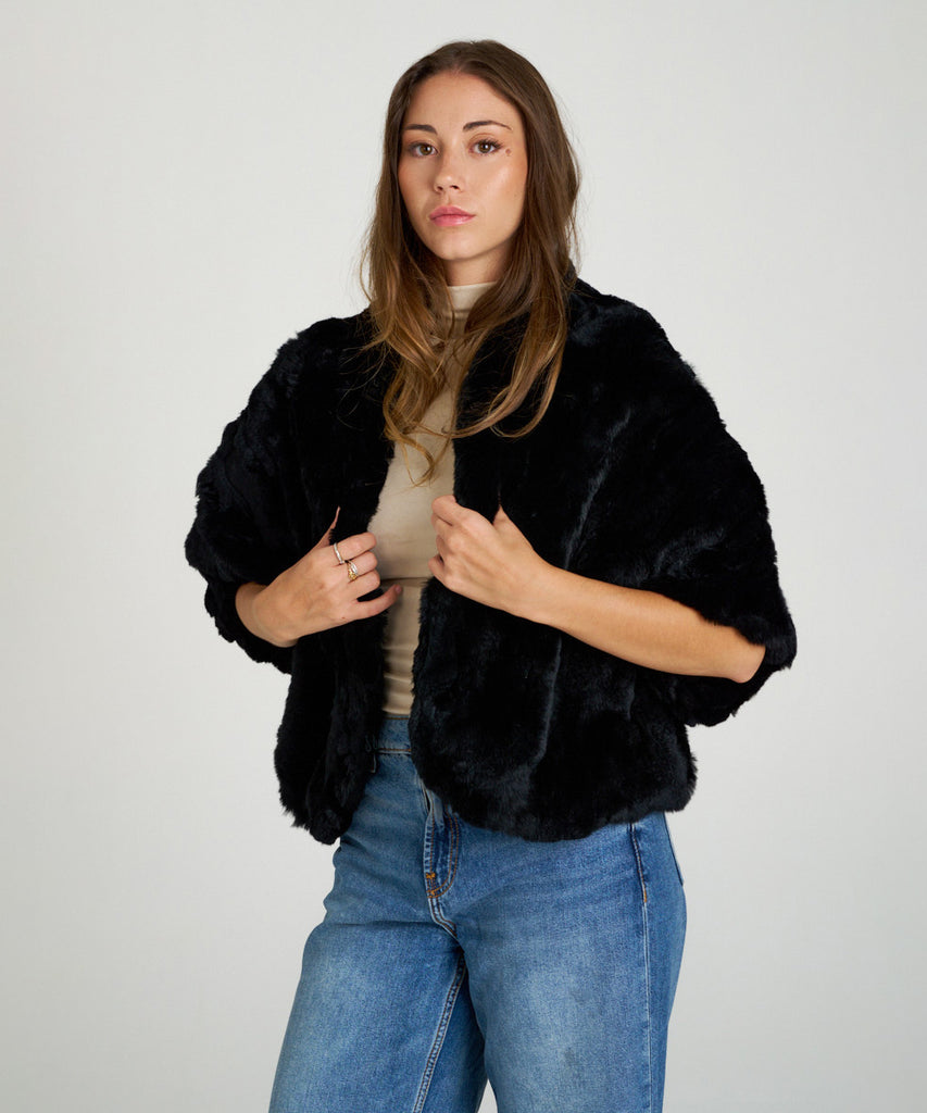 Capa corta de piel de rex negro de Hervás Piel, diseño artesanal de peletería española con manga francesa y cierre oculto.