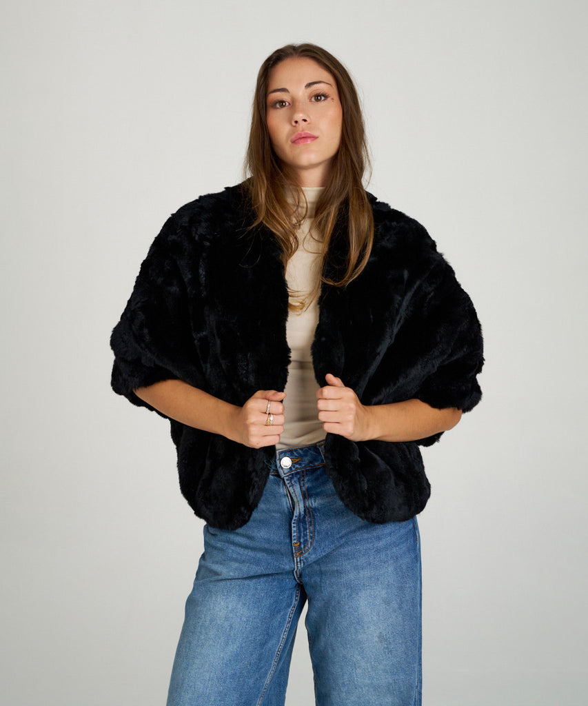 Capa corta de piel de rex negro de Hervás Piel, diseño artesanal de peletería española con manga francesa y cierre oculto.