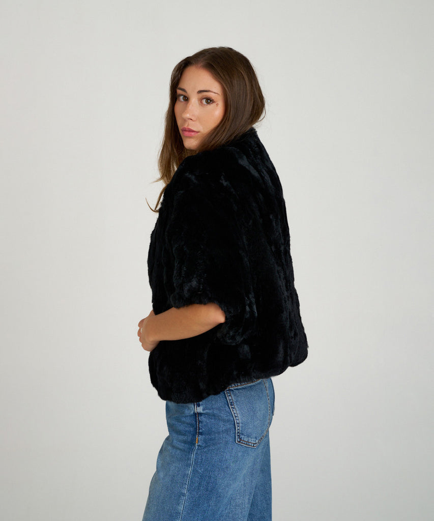 Capa corta de piel de rex negro de Hervás Piel, diseño artesanal de peletería española con manga francesa y cierre oculto.