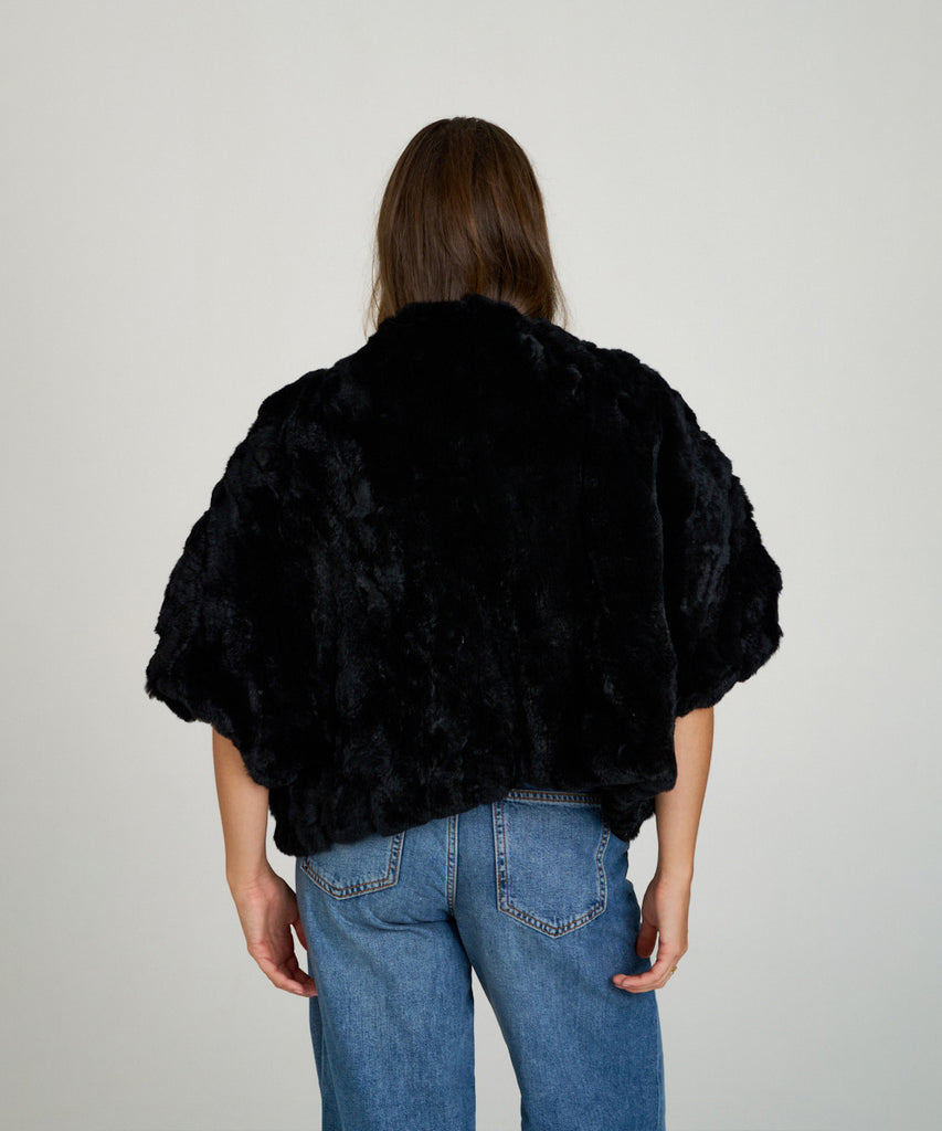 Capa corta de piel de rex negro de Hervás Piel, diseño artesanal de peletería española con manga francesa y cierre oculto.