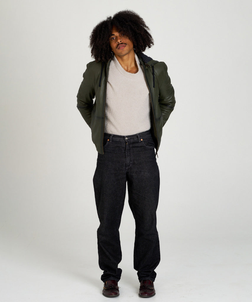 Cazadora bomber de piel verde oliva con capucha, cierre de cremallera y puños elásticos, estilo moderno y urbano.