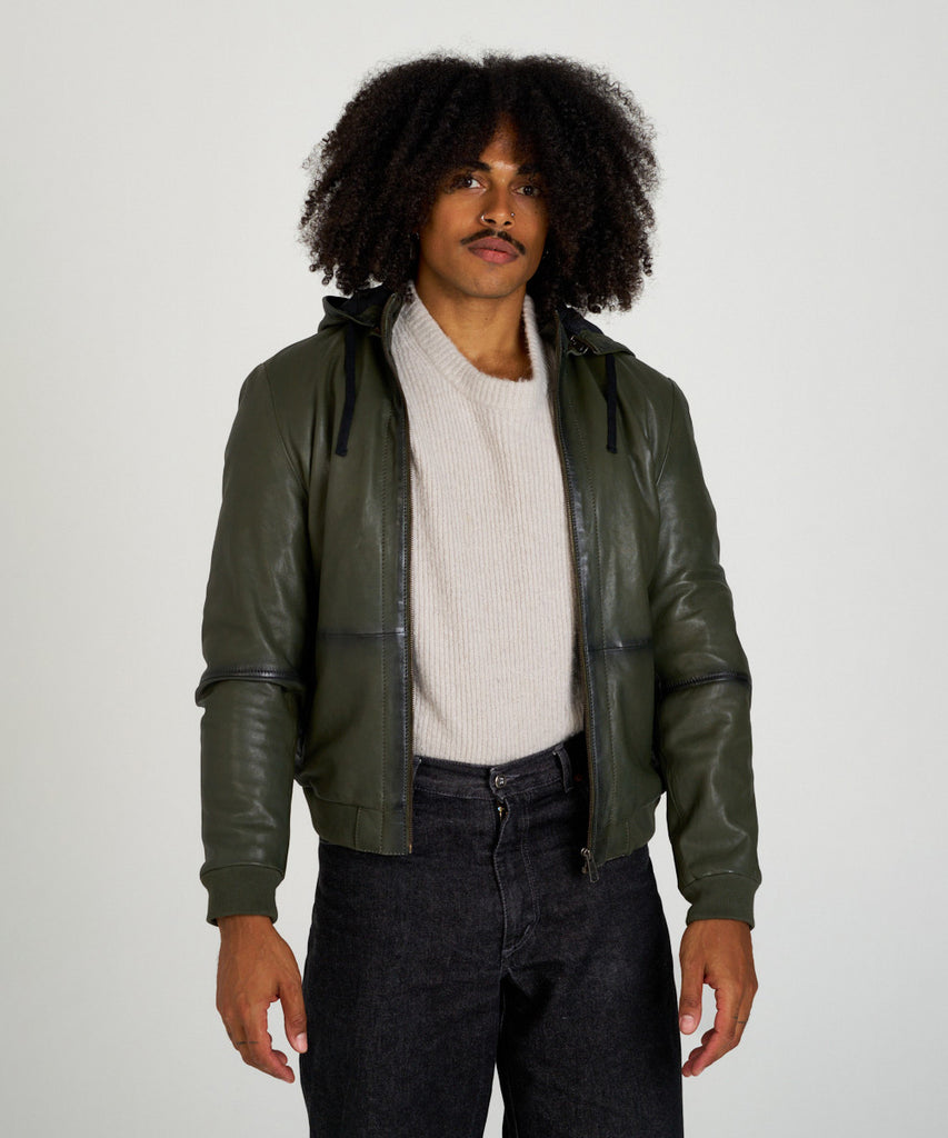 Cazadora bomber de piel verde oliva con capucha, cierre de cremallera y puños elásticos, estilo moderno y urbano.