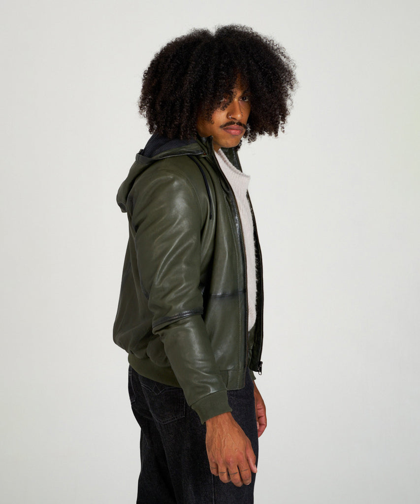 Cazadora bomber de piel verde oliva con capucha, cierre de cremallera y puños elásticos, estilo moderno y urbano.