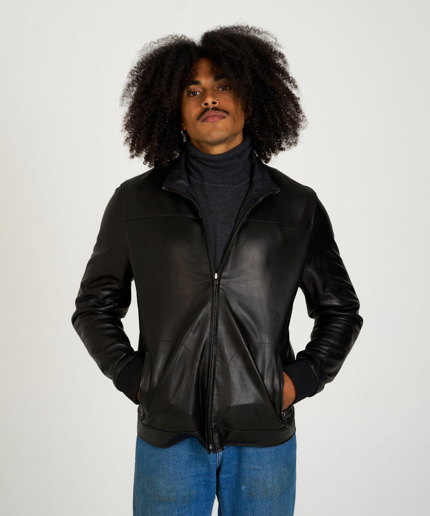 Cazadora reversible de piel napa negra con interior técnico y cremallera.