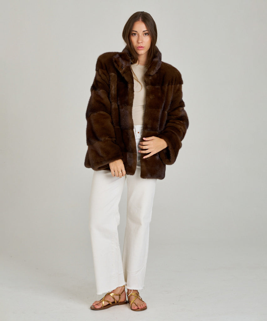 Cazadora de visón en color marrón, cuello envolvente y cierre oculto. Piel natural, corte recto y ligereza excepcional. Elegante, cálida y atemporal.