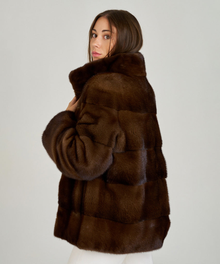 Cazadora de visón en color marrón, cuello envolvente y cierre oculto. Piel natural, corte recto y ligereza excepcional. Elegante, cálida y atemporal.