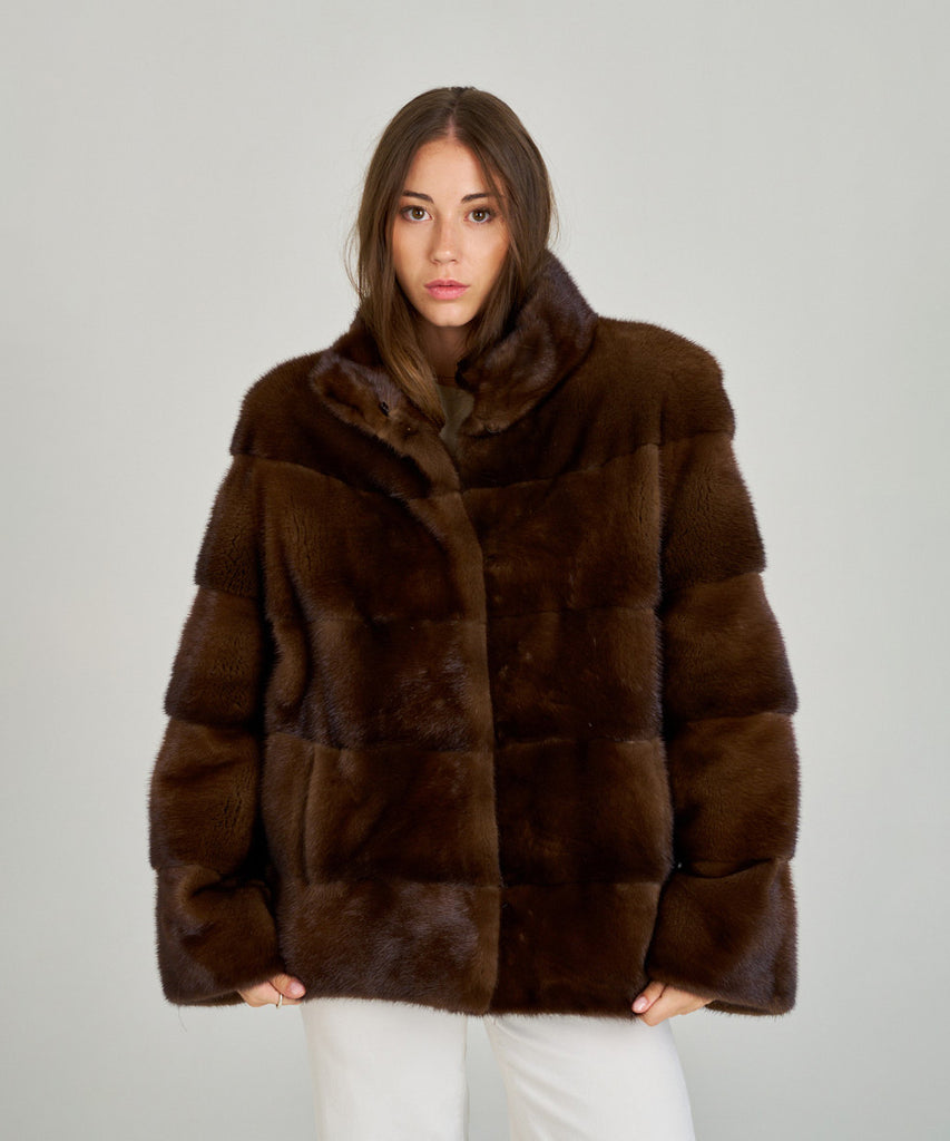 Cazadora de visón en color marrón, cuello envolvente y cierre oculto. Piel natural, corte recto y ligereza excepcional. Elegante, cálida y atemporal.