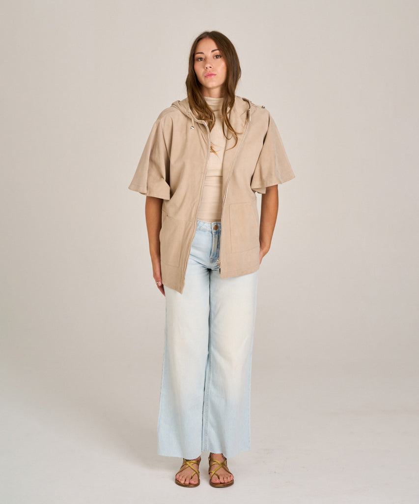 Chaqueta de ante color arena con capucha y manga corta. Diseño relajado, suave y versátil, perfecta para entretiempo.