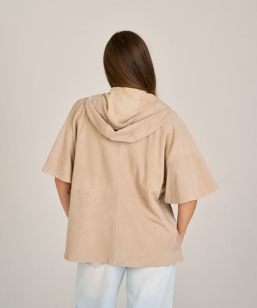 Chaqueta de ante color arena con capucha y manga corta. Diseño relajado, suave y versátil, perfecta para entretiempo.