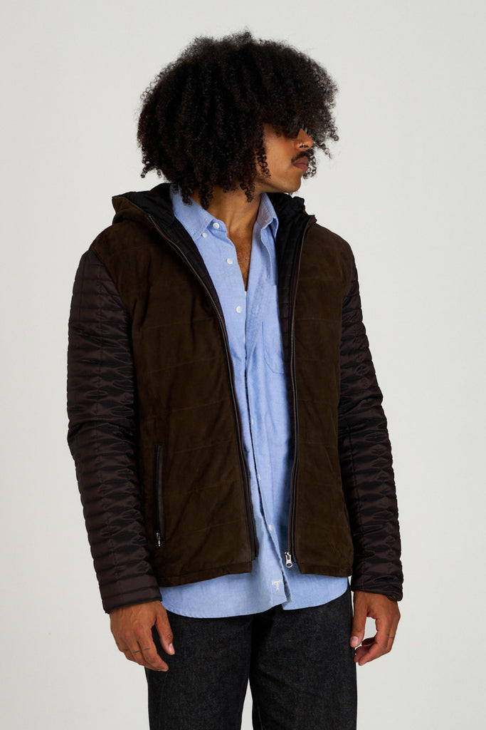 Chaqueta de piel para hombre en ante y napa marrón con mangas acolchadas, modelo vistiendo camisa azul y vaqueros, Hervás Piel.