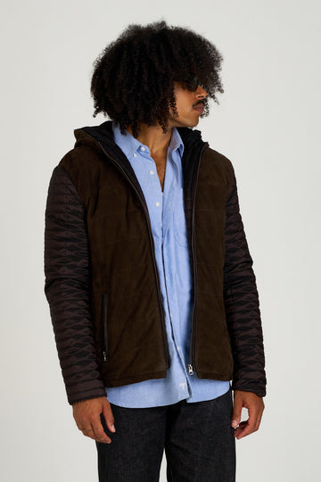 Chaqueta de piel para hombre en ante y napa marrón con mangas acolchadas, modelo vistiendo camisa azul y vaqueros, Hervás Piel.