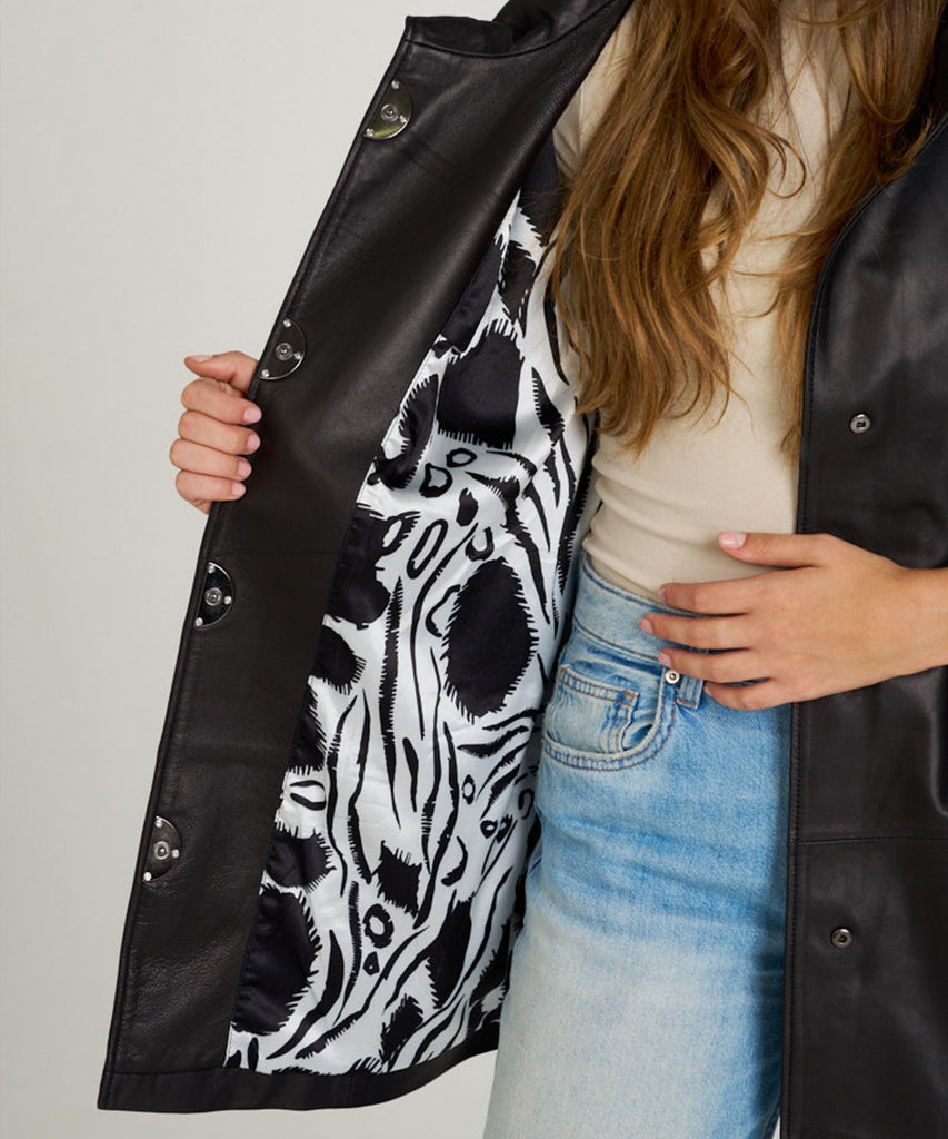 Chaqueta de piel negra para mujer. Diseño moderno con manga tres cuartos y botones a presión. Ligera, elegante y muy versátil.