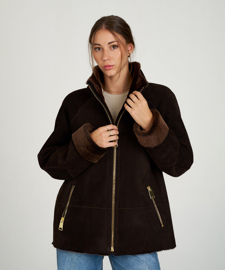 Chaqueta de piel vuelta marrón oscuro para mujer HervásPiel, con interior de borrego y cremallera dorada.