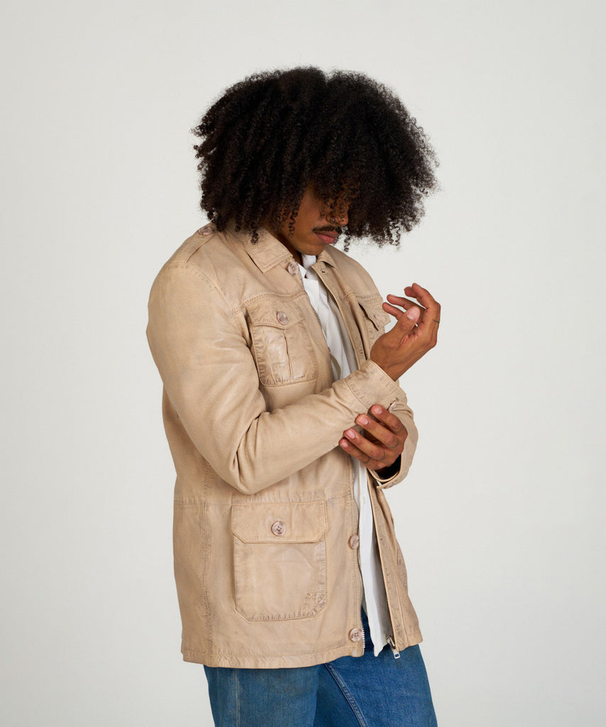 Chaqueta sahariana de piel color arena para hombre HervásPiel, con bolsillos frontales, cierre de cremallera y tapeta con botones.