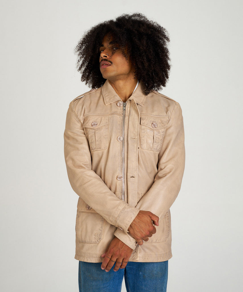 Chaqueta sahariana de piel color arena para hombre HervásPiel, con bolsillos frontales, cierre de cremallera y tapeta con botones.