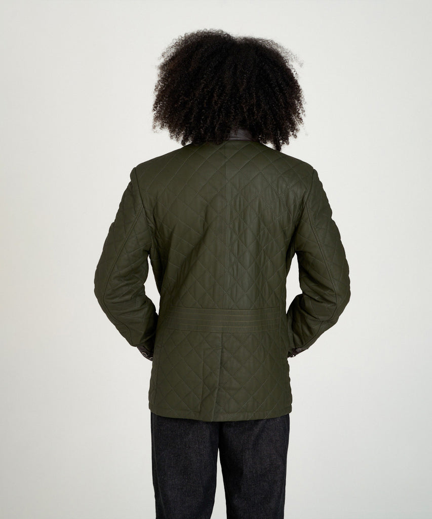 Chaqueta acolchada verde de piel con cuello alto y hebilla, estilo urbano y elegante.